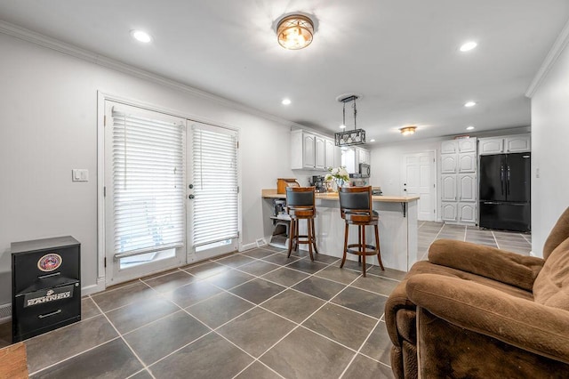 204 Tecumseh Trl, Frankfort, KY 40601 - kitchen featuring freestanding refrigerator, a peninsula, dark tile patterned flooring, crown molding, and a breakfast bar area