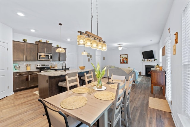 137 Kirkstall Way, Georgetown, KY 40324 - dining room with a ceiling fan, light wood-style floors, a warm lit fireplace, and recessed lighting