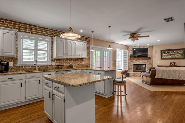 2609 Idlewood Dr, Lexington, KY 40513 - kitchen with a peninsula, a ceiling fan, a kitchen island, a large fireplace, and plenty of natural light