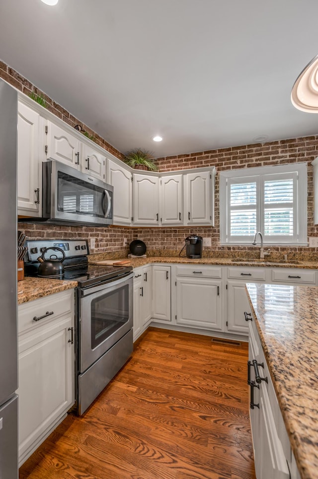 2609 Idlewood Dr, Lexington, KY 40513 - kitchen featuring stainless steel appliances, white cabinets, decorative backsplash, light stone countertops, and wood finished floors
