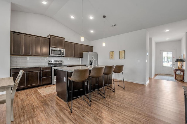 117 Mcafee Dr, Nicholasville, KY 40356 - kitchen with appliances with stainless steel finishes, a breakfast bar area, a center island with sink, dark brown cabinets, and wood finished floors