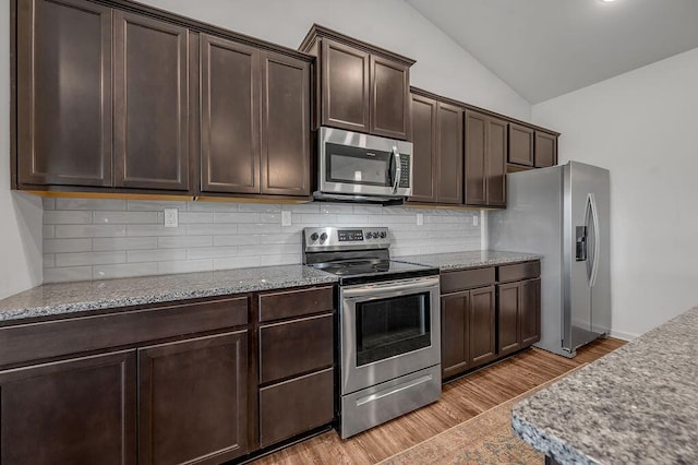 117 Mcafee Dr, Nicholasville, KY 40356 - kitchen with stainless steel appliances, vaulted ceiling, dark brown cabinets, light wood finished floors, and backsplash
