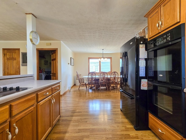 1445 Bastin Creek Rd, Kings Mountain, KY 40442 - kitchen featuring black appliances, a textured ceiling, brown cabinets, light wood-type flooring, and light countertops