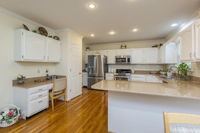 4129 Amberwood Ct, Lexington, KY 40513 - kitchen featuring appliances with stainless steel finishes, a peninsula, ornamental molding, wood finished floors, and light stone countertops