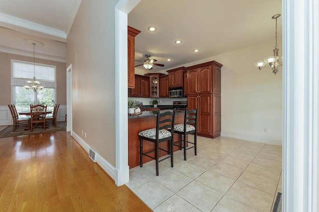 168 Master Ct, Hustonville, KY 40437 - kitchen featuring a chandelier, appliances with stainless steel finishes, dark countertops, ornamental molding, and a kitchen bar