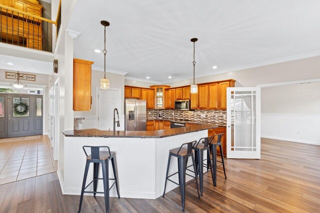 115 Westwoods Dr, Georgetown, KY 40324 - kitchen with stainless steel appliances, a peninsula, brown cabinets, light wood-type flooring, and a kitchen breakfast bar