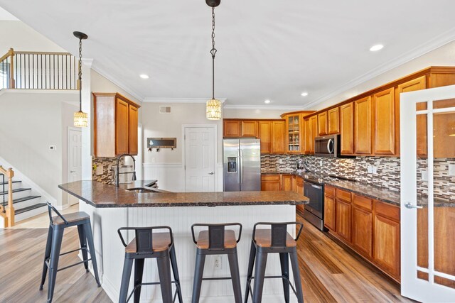 115 Westwoods Dr, Georgetown, KY 40324 - kitchen featuring stainless steel appliances, a peninsula, brown cabinets, light wood-style flooring, and glass insert cabinets