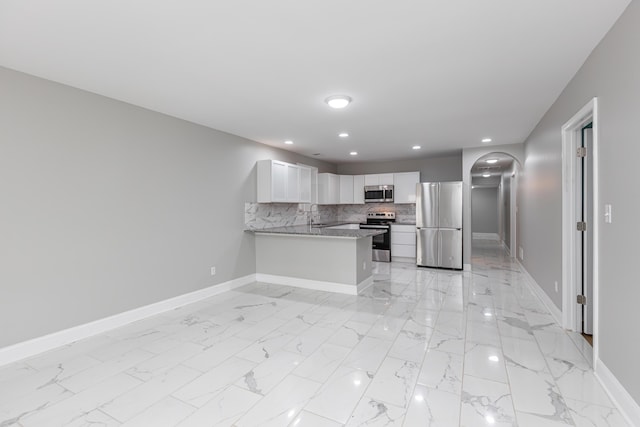 223 Race St, Lexington, KY 40508 - kitchen featuring appliances with stainless steel finishes, a peninsula, white cabinets, light marble finish floors, and tasteful backsplash