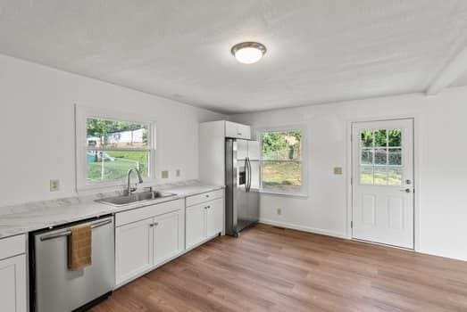 1142 Kiowa Trl, Frankfort, KY 40601 - kitchen with appliances with stainless steel finishes, light wood-style flooring, white cabinetry, and light countertops