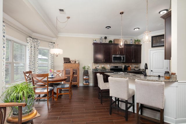 136 Rocky Creek Rd, Georgetown, KY 40324 - kitchen featuring appliances with stainless steel finishes, dark brown cabinetry, decorative backsplash, light stone counters, and a kitchen bar