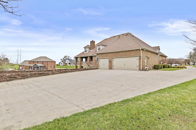 117 Richland Dr, Richmond, KY 40475 - view of side of home featuring an attached garage, concrete driveway, brick siding, a chimney, and roof with shingles