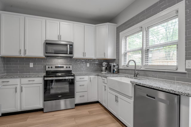 1074 Rockbridge Rd, Lexington, KY 40515 - kitchen with appliances with stainless steel finishes, white cabinetry, tasteful backsplash, light stone counters, and light wood finished floors