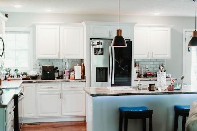 585 Cotton Rd, Corbin, KY 40701 - kitchen featuring stainless steel refrigerator with ice dispenser, black range with electric stovetop, tasteful backsplash, a breakfast bar, and white cabinetry