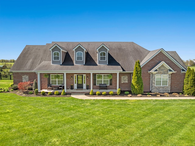 111 Colonial Dr, Versailles, KY 40383 - cape cod home featuring a front lawn, covered porch, brick siding, and roof with shingles