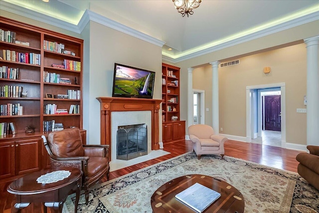 1758 Airdrie Ln, Frankfort, KY 40601 - living room featuring ornate columns, a fireplace with flush hearth, built in shelves, wood finished floors, and ornamental molding