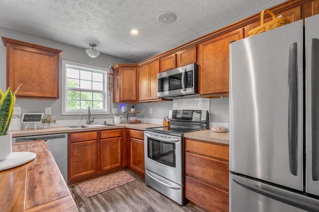 1701 Keating Dr, Louisville, KY 40245 - kitchen featuring stainless steel appliances, light wood finished floors, light countertops, brown cabinets, and a textured ceiling