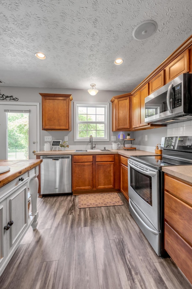 1701 Keating Dr, Louisville, KY 40245 - kitchen featuring appliances with stainless steel finishes, light wood finished floors, brown cabinets, a textured ceiling, and recessed lighting