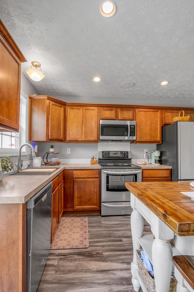 1701 Keating Dr, Louisville, KY 40245 - kitchen featuring stainless steel appliances, wood finished floors, brown cabinetry, a textured ceiling, and recessed lighting