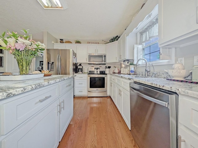 109 Edwards Ct, Lancaster, KY 40444 - kitchen with appliances with stainless steel finishes, white cabinets, light wood-type flooring, light stone counters, and a textured ceiling