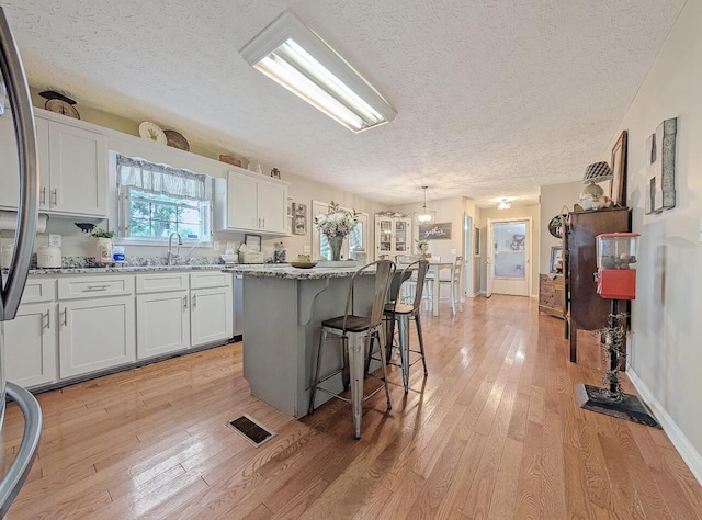 109 Edwards Ct, Lancaster, KY 40444 - kitchen featuring a center island, a kitchen breakfast bar, light wood finished floors, white cabinets, and a textured ceiling