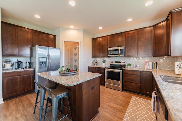 126 Mollie Way, Georgetown, KY 40324 - kitchen with stainless steel appliances, decorative backsplash, a kitchen island, light wood-style flooring, and a kitchen bar