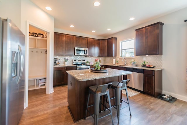 126 Mollie Way, Georgetown, KY 40324 - kitchen featuring stainless steel appliances, light wood-style flooring, dark brown cabinetry, a kitchen island, and a kitchen breakfast bar