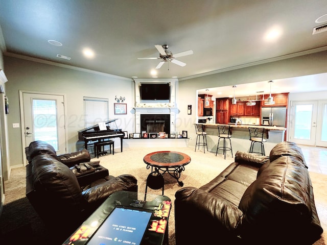 living room with a ceiling fan, a large fireplace, light colored carpet, ornamental molding, and visible vents
