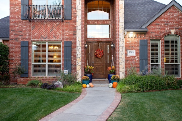 7705 New England Pkwy, Amarillo, TX 79119 - view of exterior entry featuring a yard, a shingled roof, and brick siding