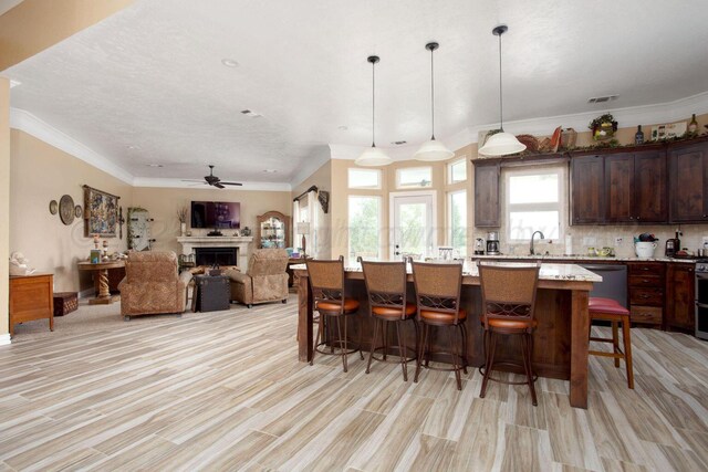 6106 Purple Sage Cir, Amarillo, TX 79124 - kitchen with a breakfast bar area, a ceiling fan, a fireplace, open floor plan, and dark brown cabinetry