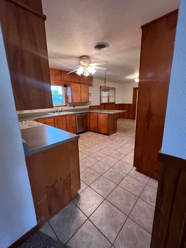 109 Ranger St, Hereford, TX 79045 - kitchen with a peninsula, brown cabinets, ceiling fan, wood walls, and dishwasher