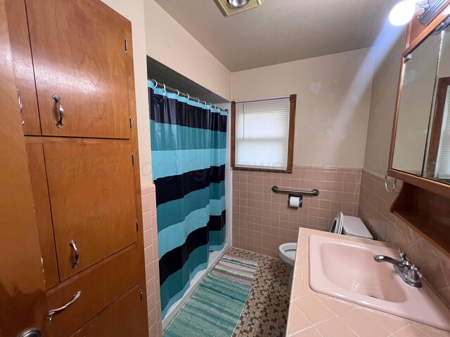 109 Ranger St, Hereford, TX 79045 - full bath featuring toilet, tile walls, curtained shower, wainscoting, and a sink