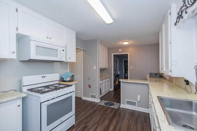 kitchen with white appliances, dark hardwood / wood-style floors, and white cabinetry