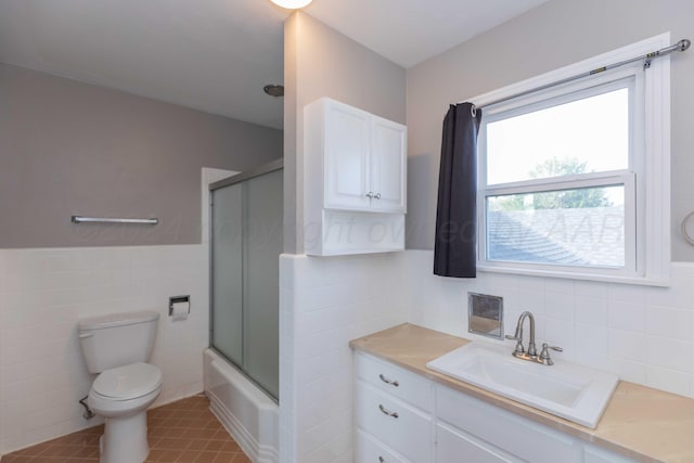 full bathroom with toilet, vanity, combined bath / shower with glass door, and tile walls