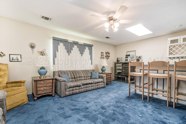 living room featuring a skylight, a ceiling fan, carpet flooring, and visible vents
