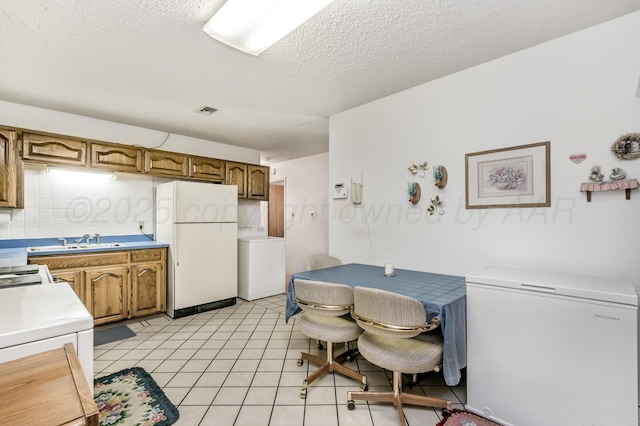 kitchen featuring a sink, light countertops, white refrigerator, freestanding refrigerator, and washer / clothes dryer
