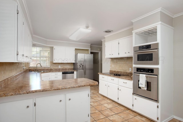 3203 S Austin St, Amarillo, TX 79109 - kitchen with appliances with stainless steel finishes, a peninsula, tasteful backsplash, ornamental molding, and white cabinetry