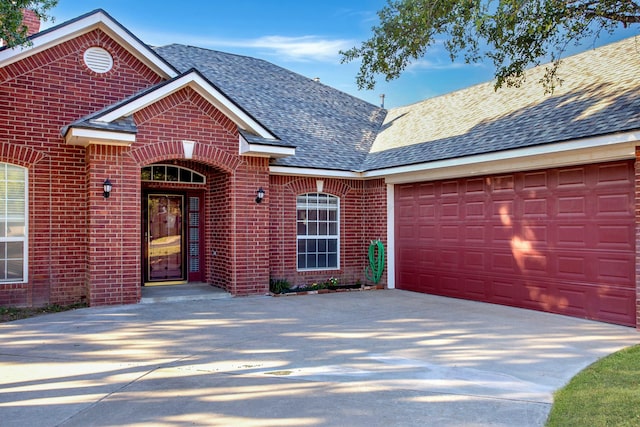 traditional home with brick siding, driveway, a shingled roof, and an attached garage