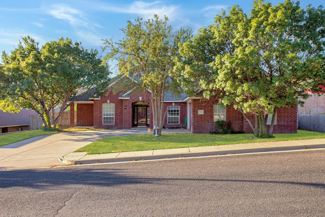 view of front of house with a front yard, fence, and brick siding