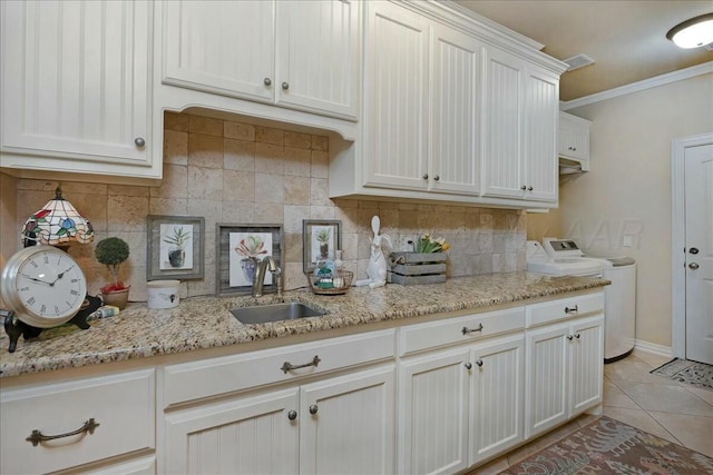 7908 London Ct, Amarillo, TX 79119 - kitchen featuring a sink, tasteful backsplash, ornamental molding, light tile patterned floors, and washing machine and dryer