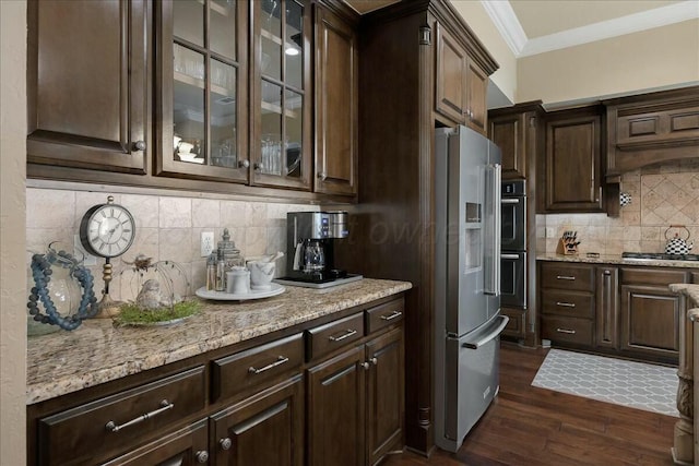 7908 London Ct, Amarillo, TX 79119 - kitchen with dark brown cabinetry, dark wood-type flooring, appliances with stainless steel finishes, decorative backsplash, and ornamental molding