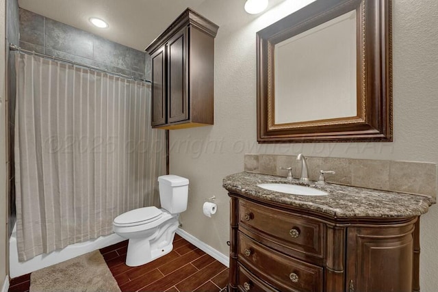 bathroom with wood finish floors, toilet, shower / tub combo, vanity, and baseboards