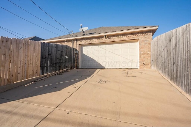 garage featuring fence and driveway