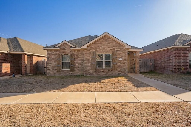 ranch-style home featuring brick siding and fence