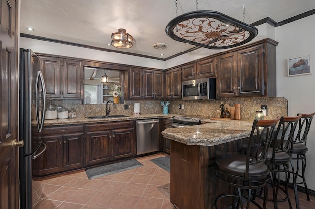 6410 Hamstead Dr, Amarillo, TX 79109 - kitchen with appliances with stainless steel finishes, dark brown cabinetry, a peninsula, tasteful backsplash, and crown molding