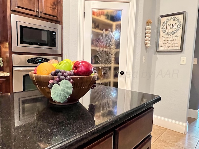 7507 Continental Pkwy, Amarillo, TX 79119 - kitchen featuring appliances with stainless steel finishes, light tile patterned flooring, and dark stone countertops