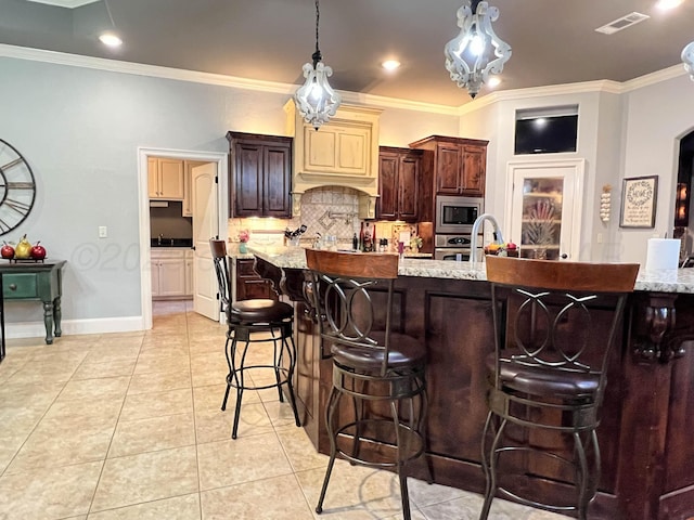 7507 Continental Pkwy, Amarillo, TX 79119 - kitchen featuring stainless steel microwave, tasteful backsplash, a kitchen breakfast bar, light tile patterned floors, and decorative light fixtures