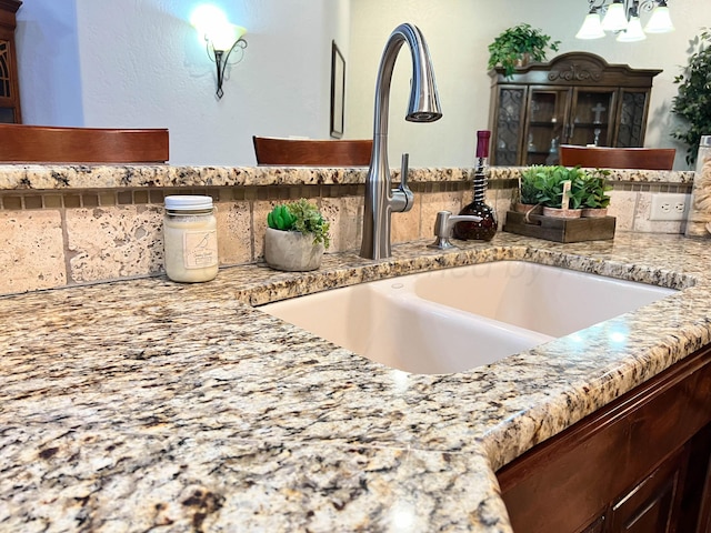 7507 Continental Pkwy, Amarillo, TX 79119 - kitchen view of a chandelier, dark brown cabinets, tasteful backsplash, and light stone counters