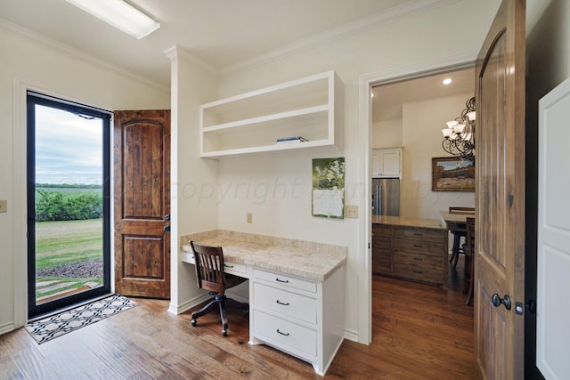 office area with built in desk, an inviting chandelier, hardwood / wood-style flooring, and ornamental molding