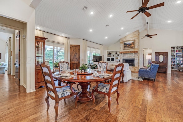 dining space with a stone fireplace, high vaulted ceiling, hardwood / wood-style flooring, and wood ceiling