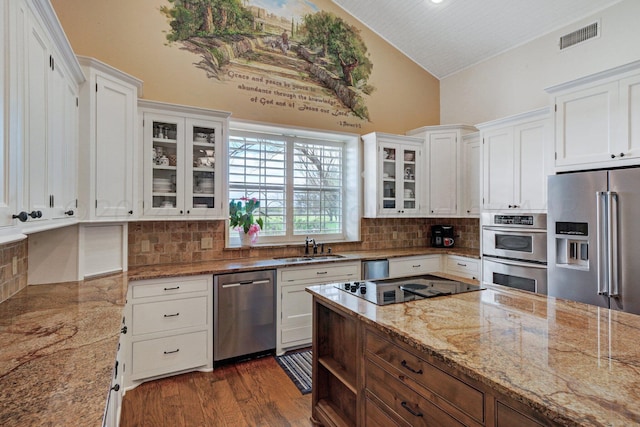 kitchen with lofted ceiling, dark wood-type flooring, white cabinets, sink, and appliances with stainless steel finishes